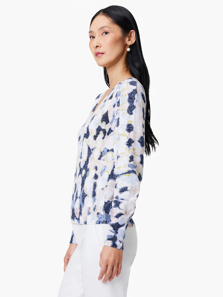 White cardigan with blue, beige, and green abstract print. Long sleeves, V-neck.
