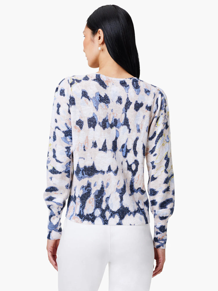 Beige sweater with blue and purple abstract print. Long sleeves, slightly puffed shoulders.