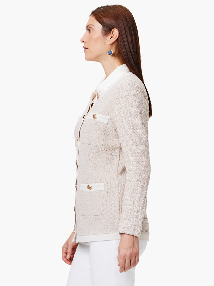 Beige knit jacket with gold buttons, white trim, and patch pockets. Side view.