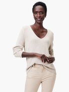 Light beige, visible knit V-neck sweater with long sleeves and a relaxed fit.