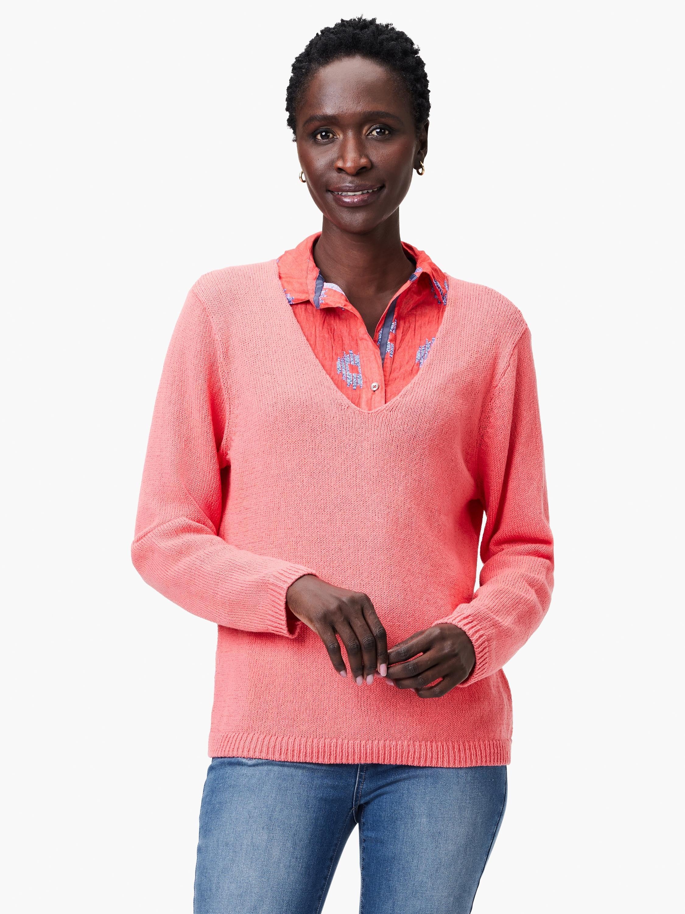 Coral knit V-neck sweater with ribbed cuffs and hem, modeled over a patterned shirt.