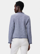 Blue & white mixed knit jacket with fringe trim at collar, hem, & cuffs, worn by a model from behind.