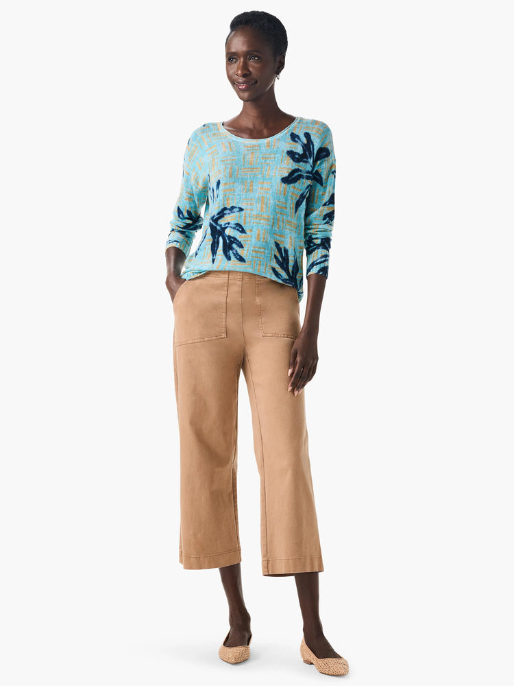 Light blue sweater with dark blue and gold leaf pattern. Long sleeves.