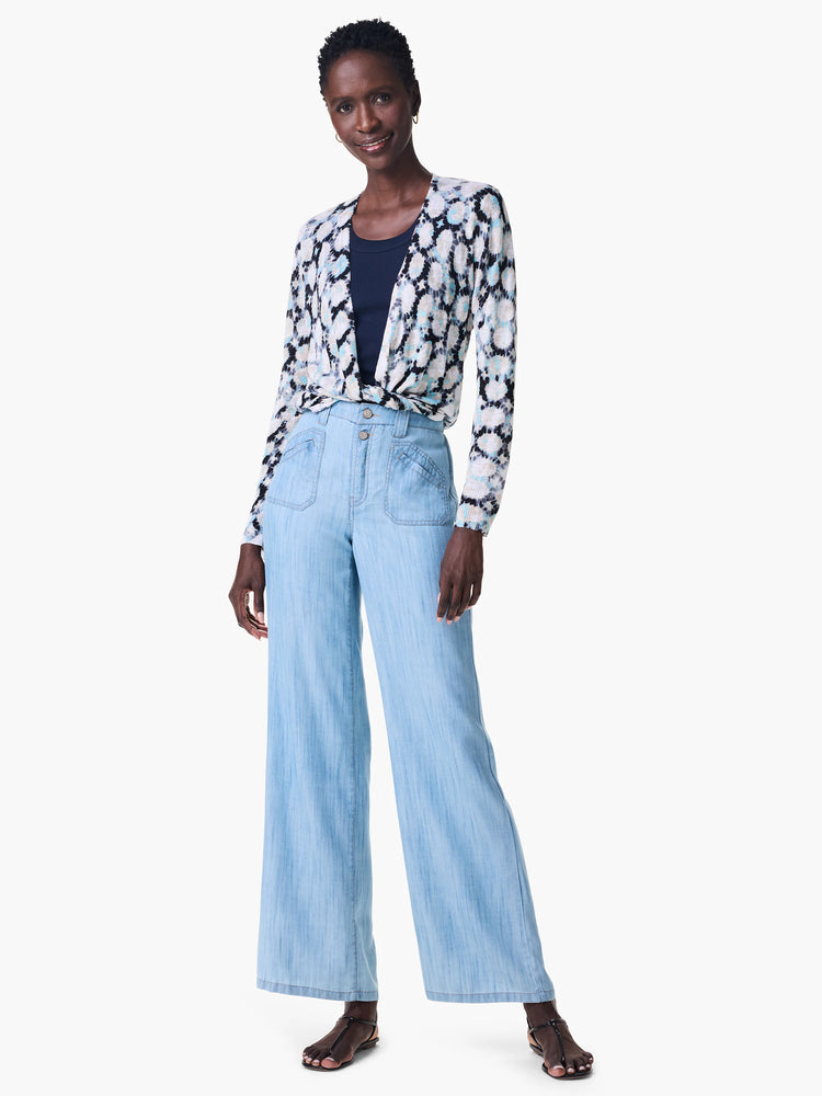 Off-white cardigan with blue and black abstract print, tied at waist. Model also wears light blue jeans and black sandals.