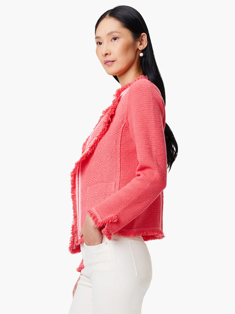 Coral knit jacket with white fringe trim. Chevron pattern. Open front.