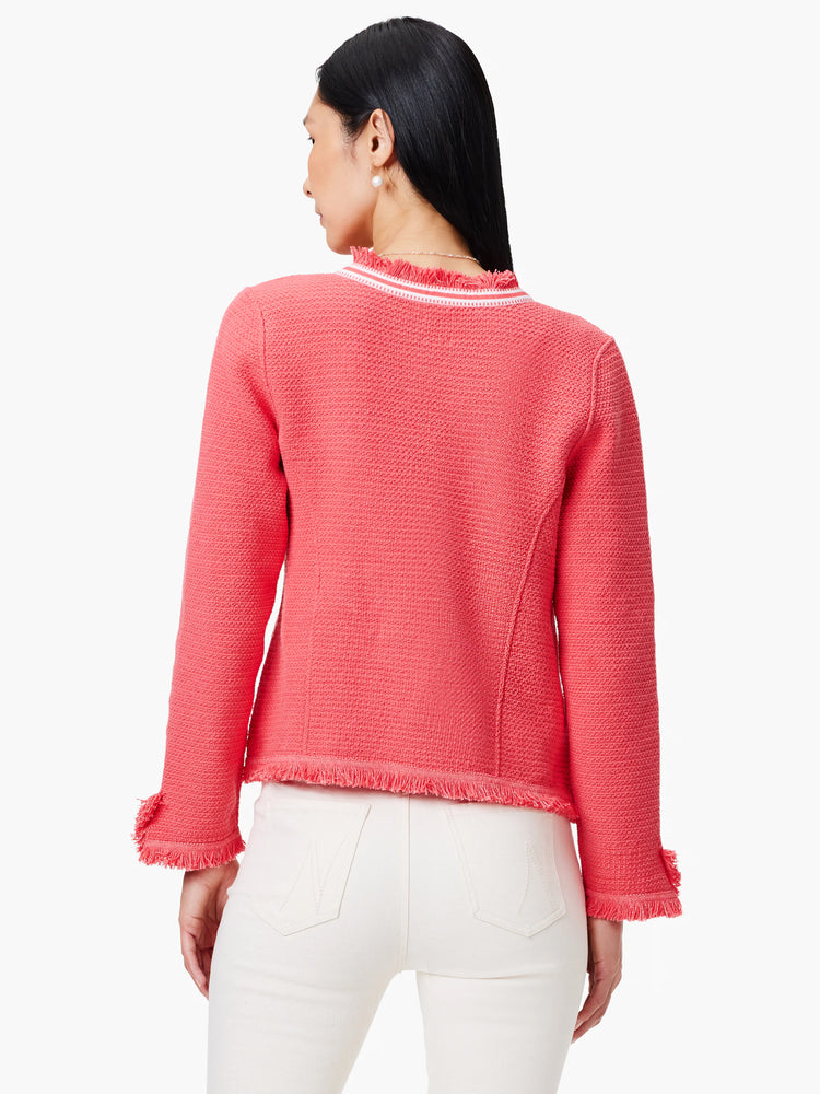 Coral knit jacket with white trim and fringe detailing at neckline and sleeves. Textured fabric.