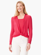 Bright coral pink cardigan with long sleeves, tied in a front knot. Features subtle textured knit on shoulders.