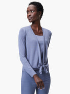 Periwinkle blue open cardigan with subtle sleeve texture, tied at front waist. Worn over matching tank top and darker pants.