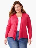 Bright coral pink open-front cardigan with a draped hem, long sleeves, and ribbed cuffs, worn over a white top.