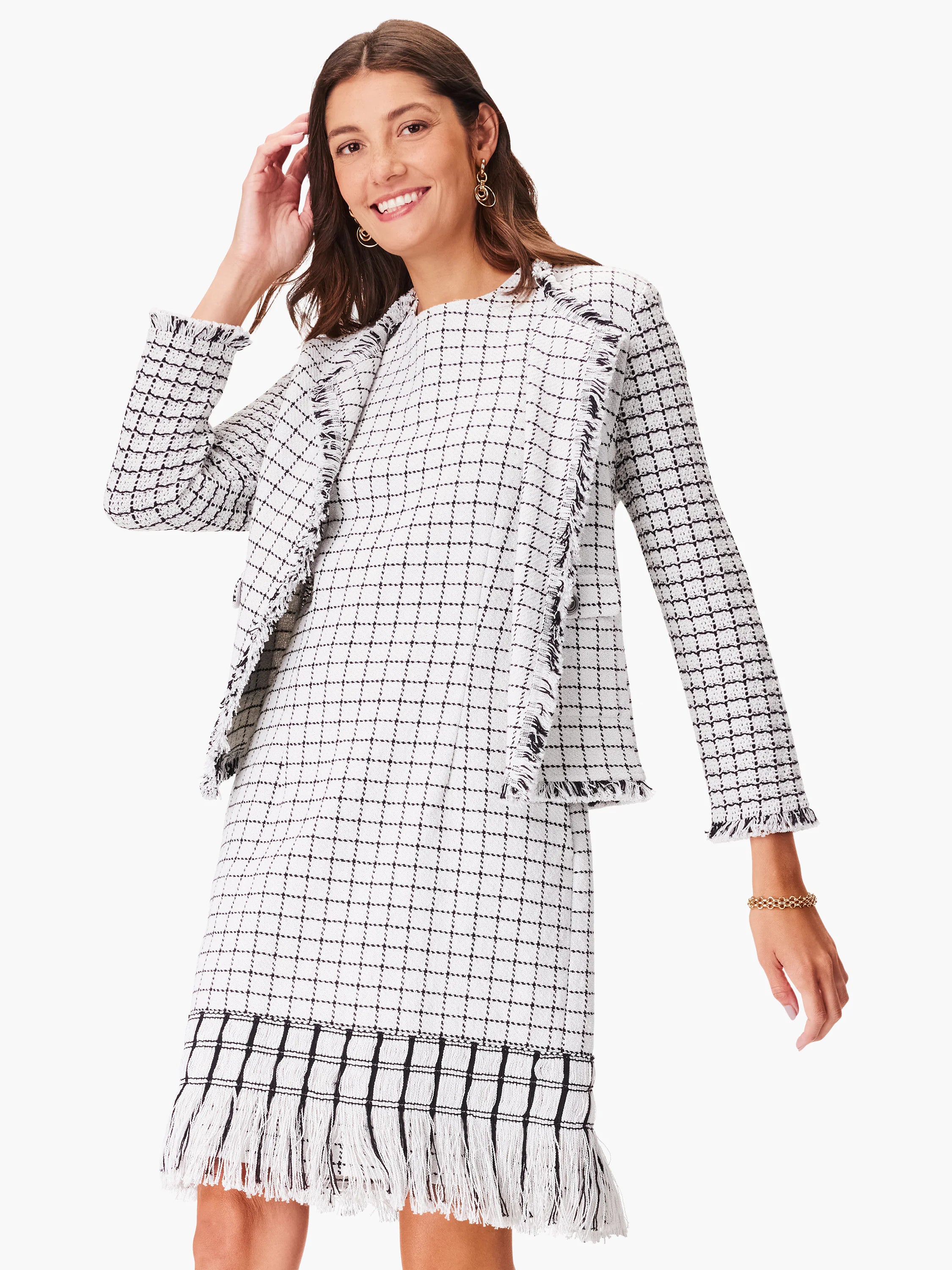 White dress with black grid pattern and fringe trim. Long sleeves.