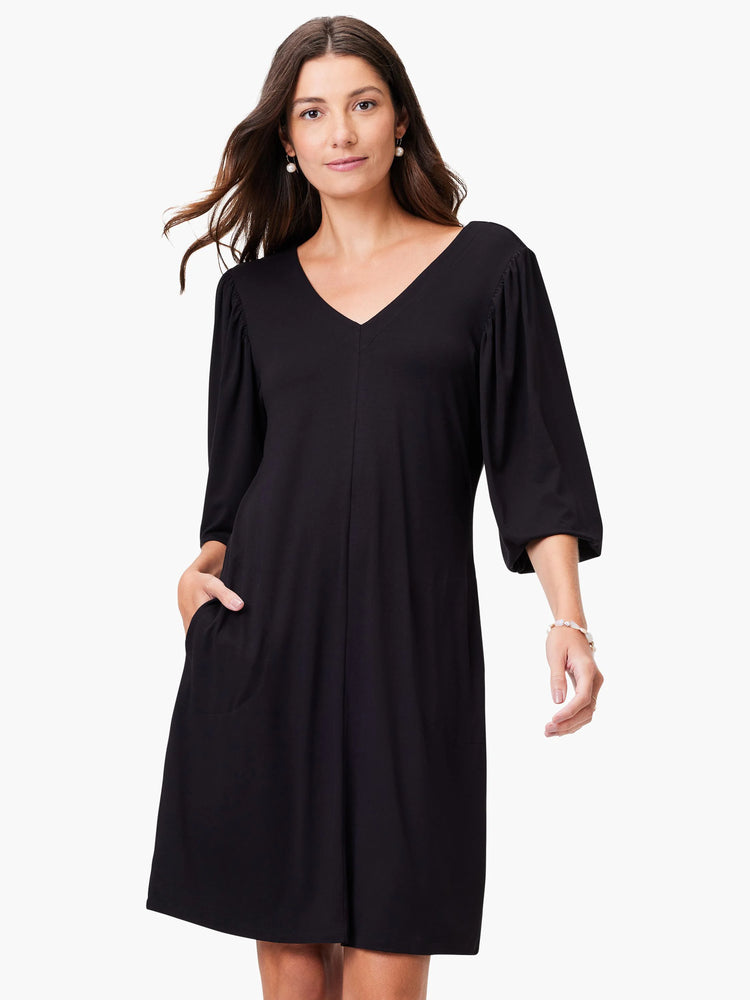 Black V-neck knit dress, 3/4 sleeves, slight puff at shoulder, knee-length, and side pockets.