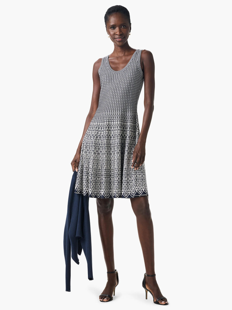 Navy and white geometric patterned sleeveless fit-and-flare dress. A navy cardigan is shown draped over the model's arm.