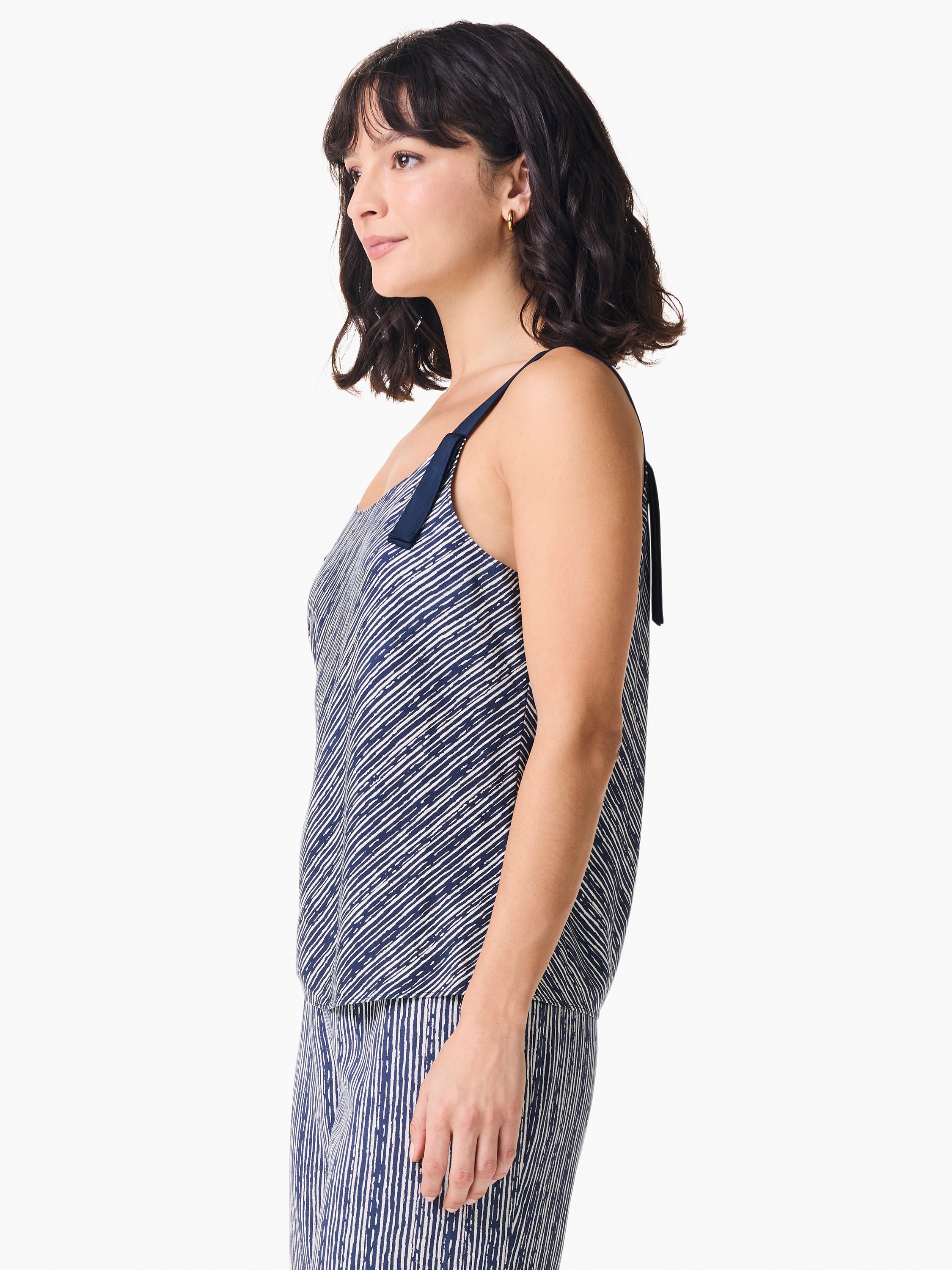 The model wears a loose navy and white striped camisole top featuring thin straps and a solid navy shoulder ribbon accent.