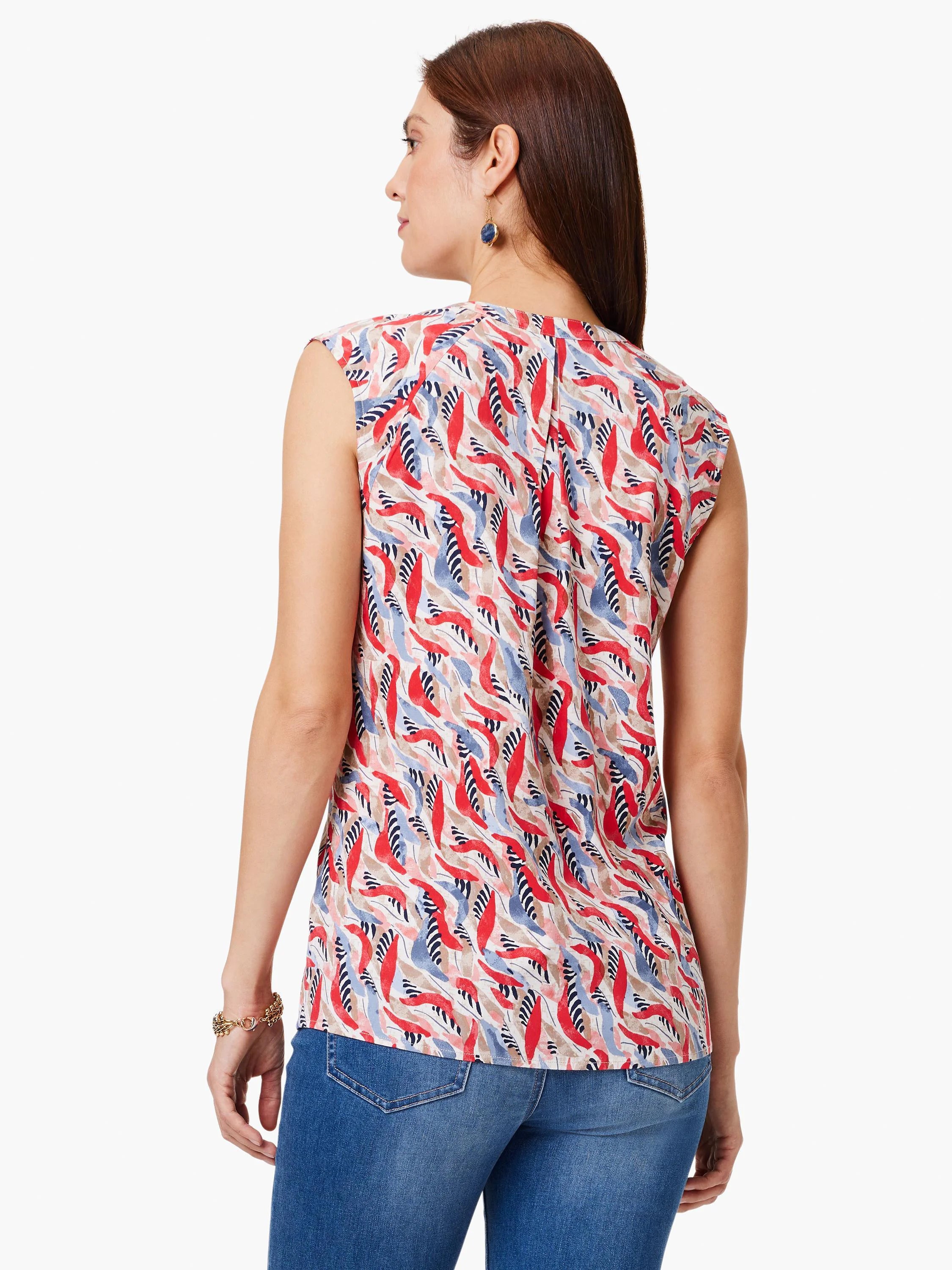 Sleeveless, cream top with red, blue, and black abstract leaf print. V-neck back.