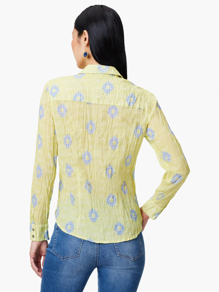 Pale yellow long-sleeved shirt, crinkled texture. Features a blue and white geometric pattern. Buttoned cuffs.