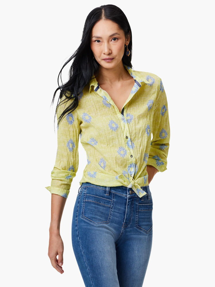 Pale yellow crinkled shirt with a blue floral pattern, long sleeves, and button closure. Knotted at the waist.