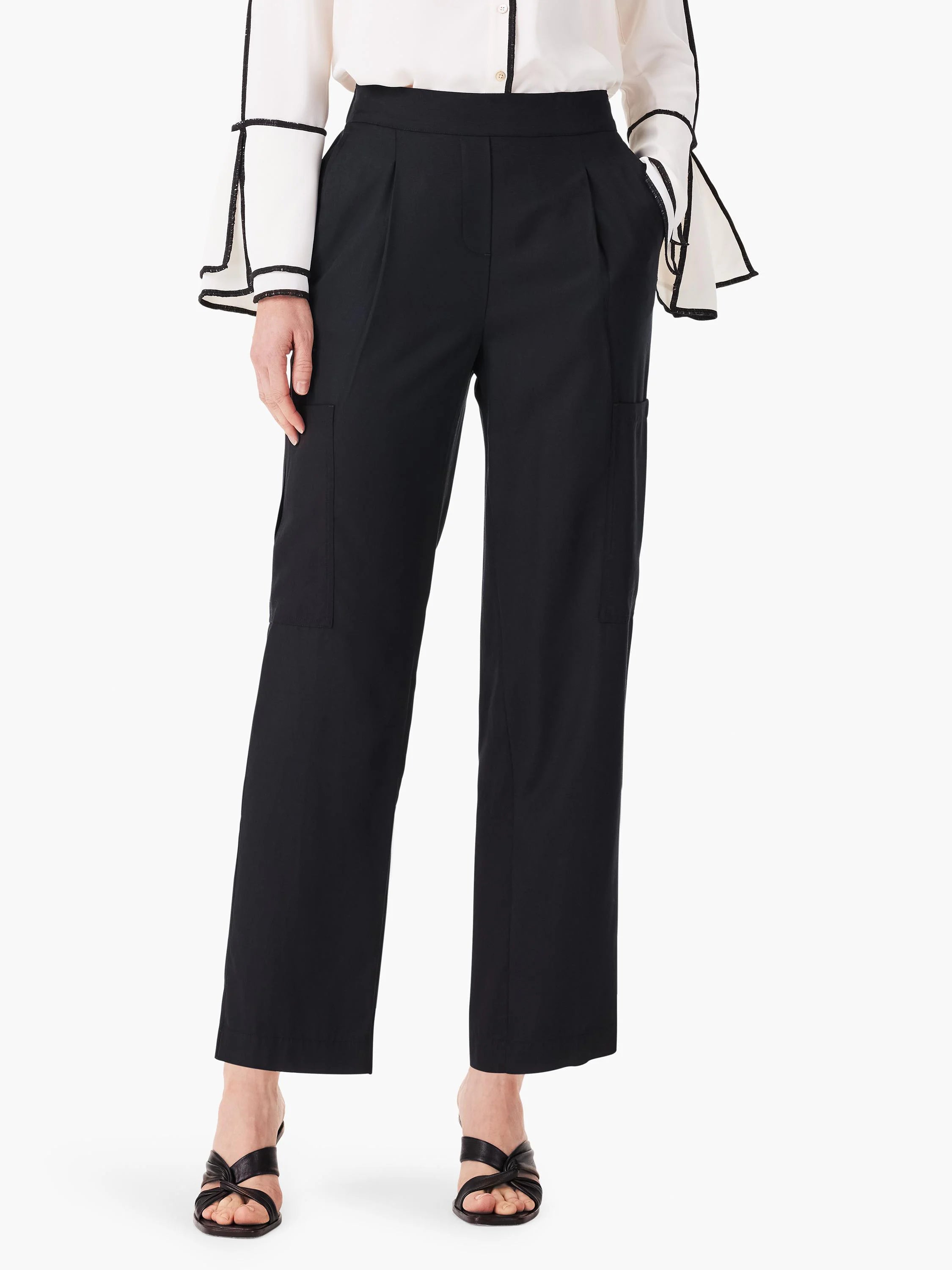 Black cargo pants; relaxed fit, pleated front, side pockets. Model shown wearing with off-white shirt.
