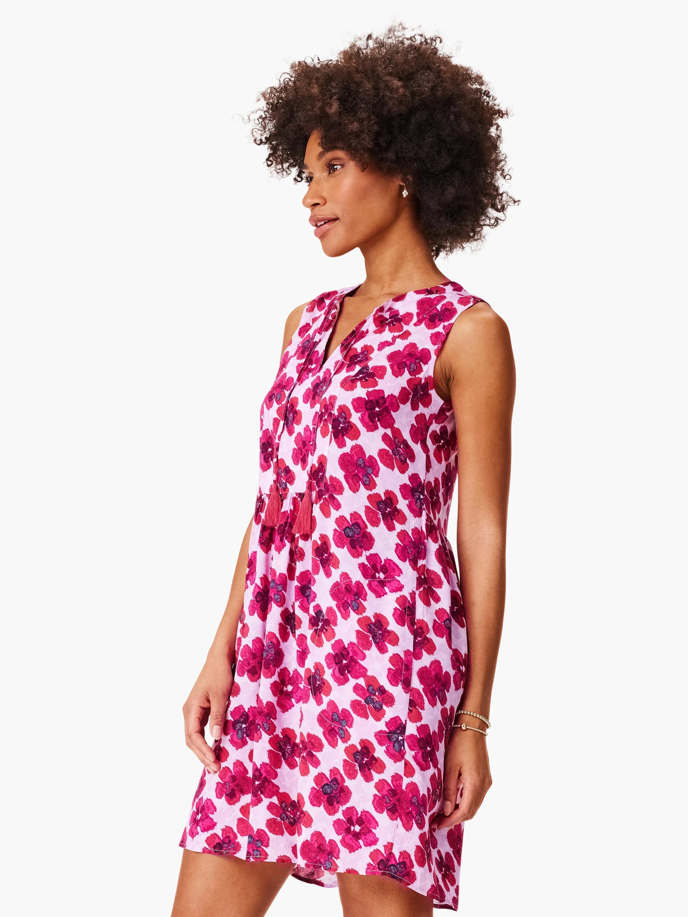 Pink sleeveless dress with a V-neck and dark pink floral print. Features small coral tassels at the neckline.