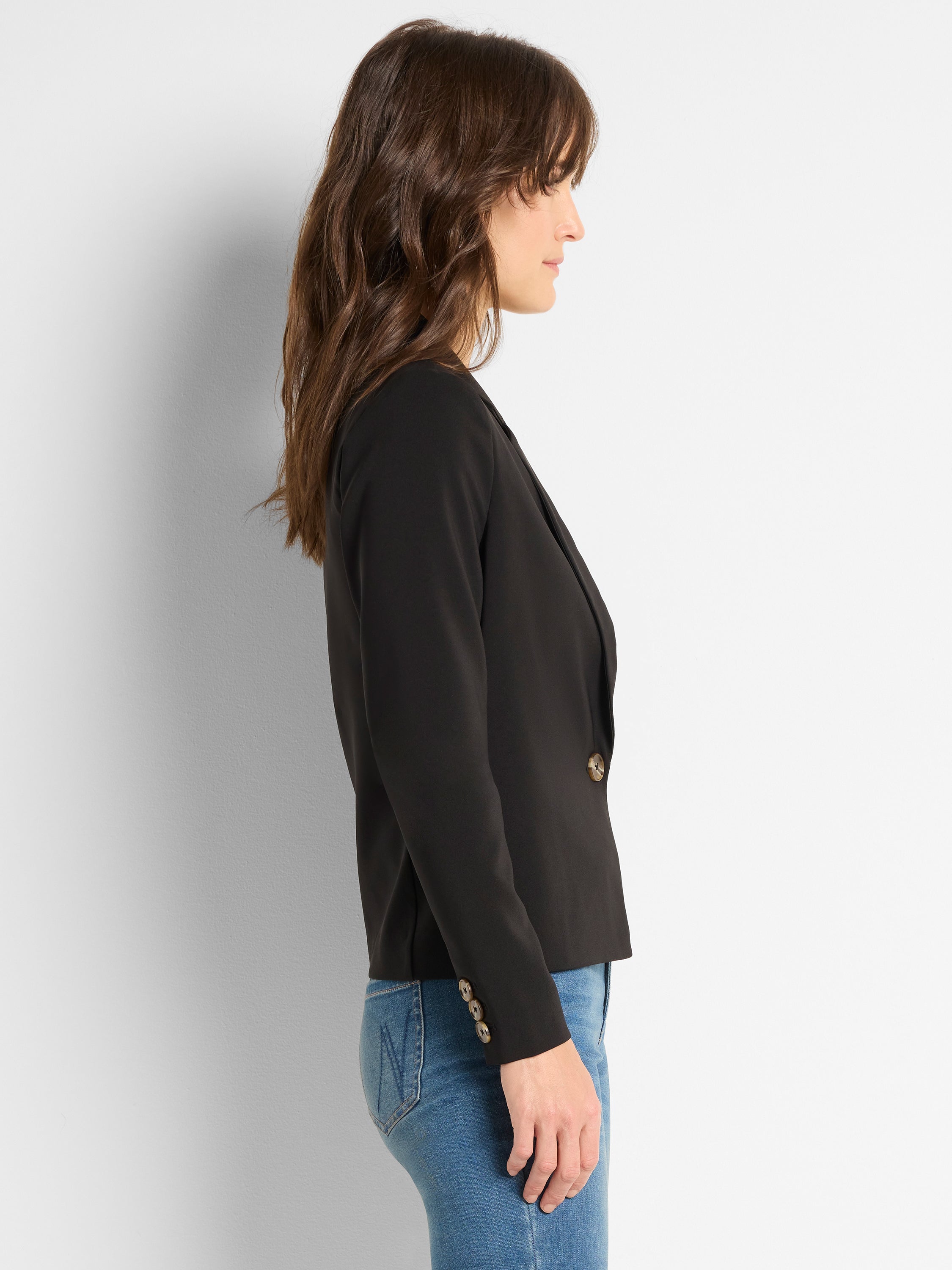 A fitted black blazer with a cropped length features a single closure button and decorative cuff buttons.