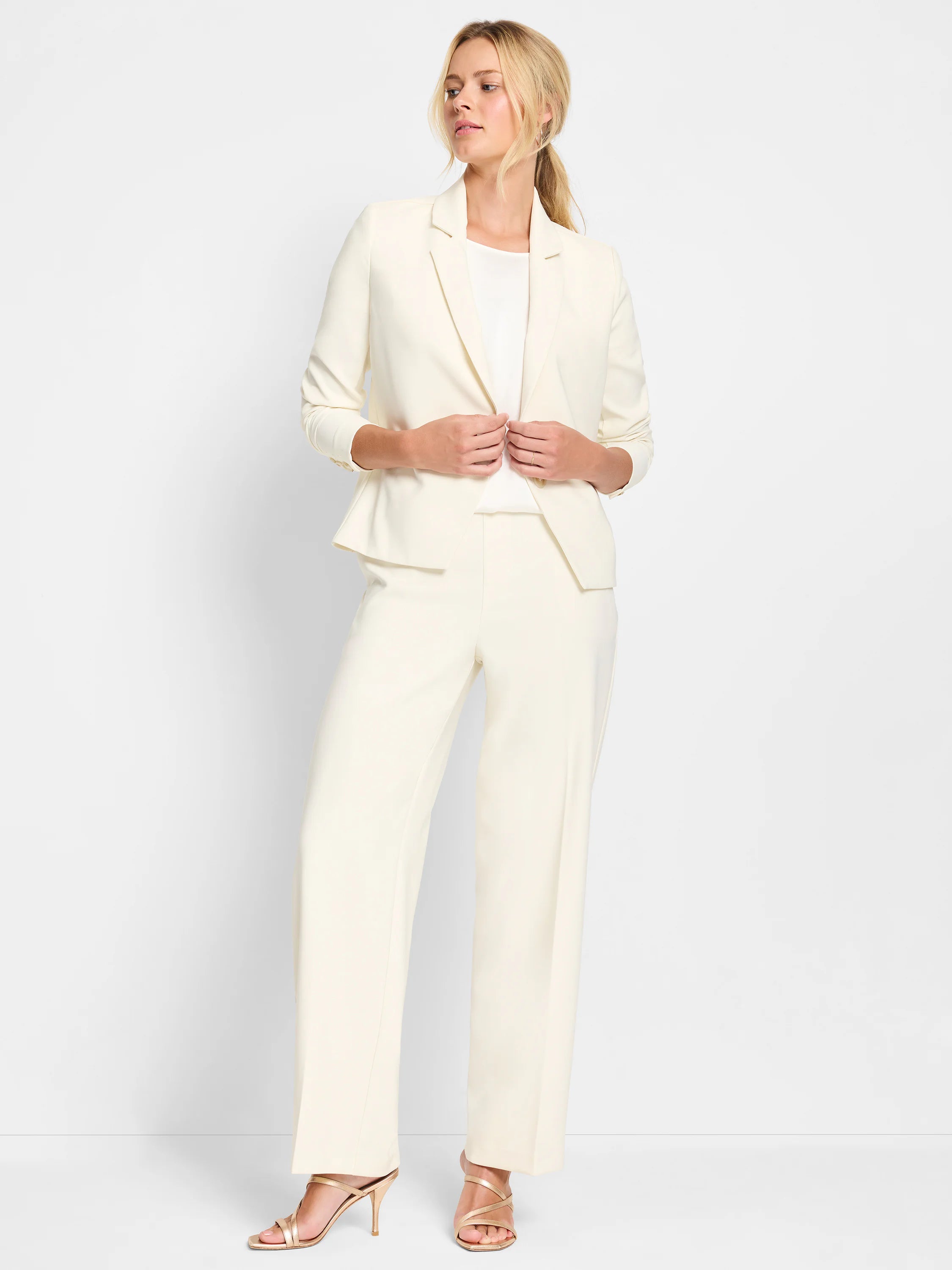 Ivory tailored blazer with classic lapels, worn with matching trousers.