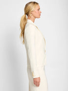 Cream blazer with a single front button closure and three cuff buttons.