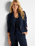 Navy blue open blazer with lapels, 3/4 length ruched sleeves, and a light brown button.
