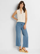 Cream sleeveless tank with a ruffled V-neckline and subtle front seams.