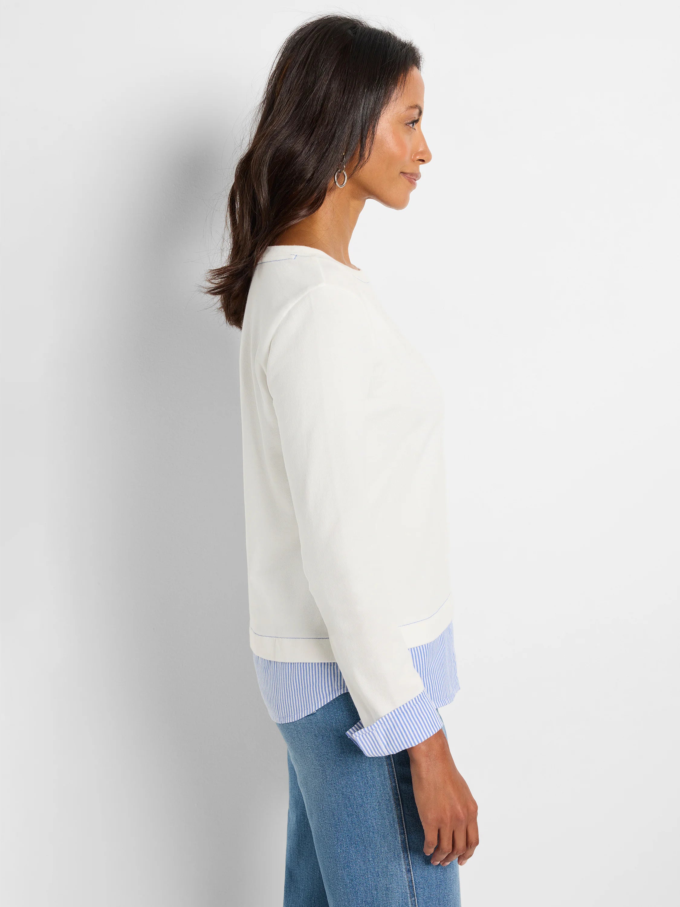 Cream long-sleeve top with blue/white striped underlayer visible at hem and folded cuffs.