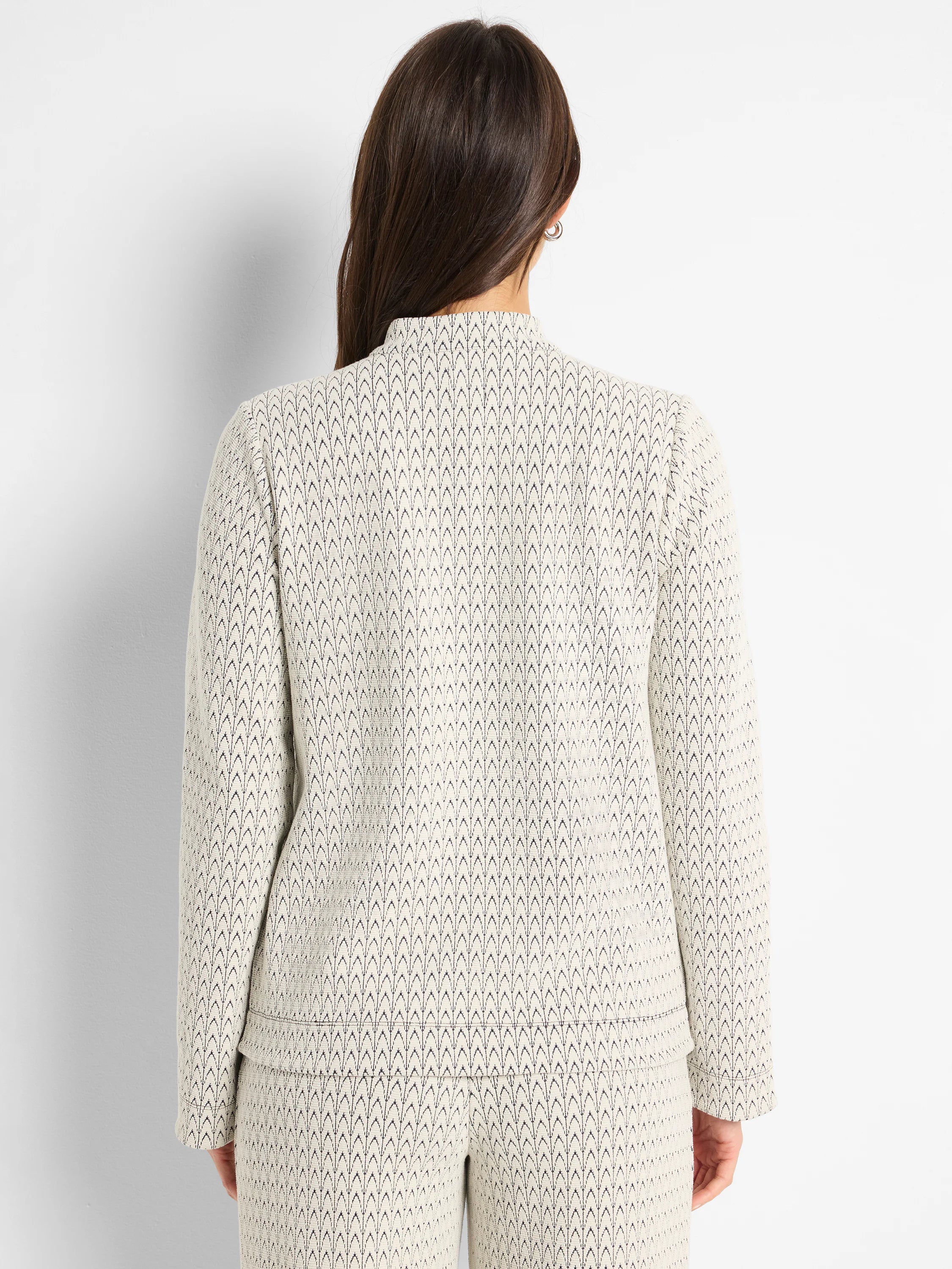 Cream knit top with subtle dark swirling pattern, mock neck, long sleeves, viewed from the back.