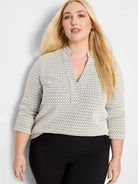 Off-white knit top with subtle dark swirl pattern, split V-neck, and 3/4 sleeves.