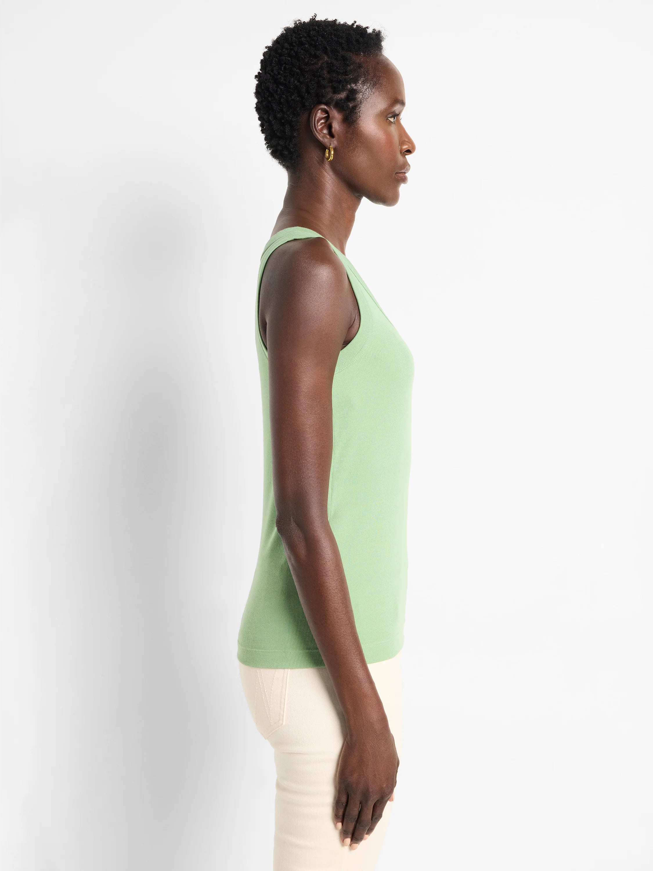 Light green ribbed knit scoop neck tank top shown on a model from the side. It has a close-fitting silhouette.