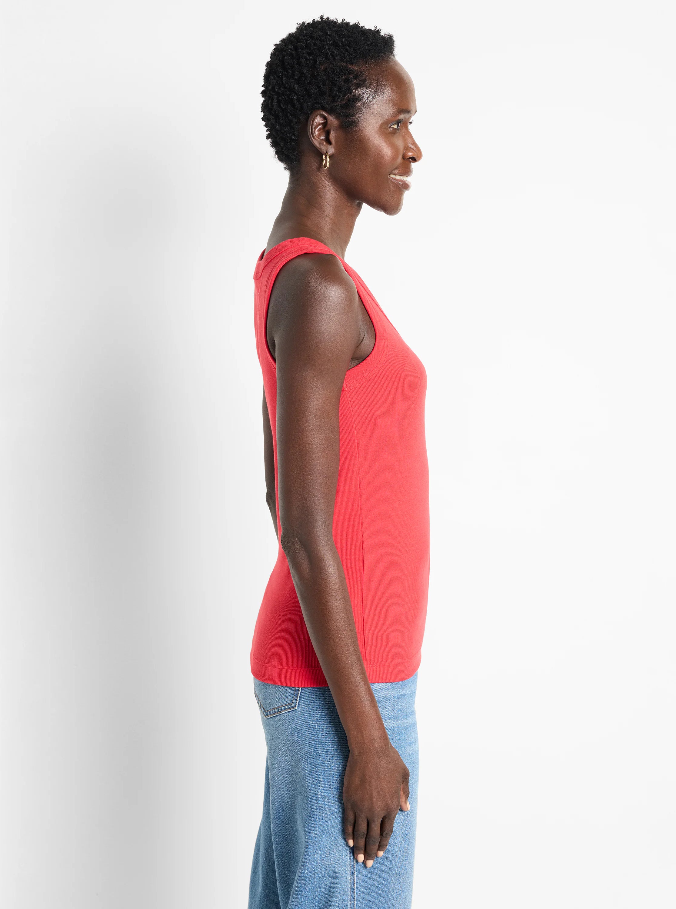 Coral ribbed scoop neck tank top worn by a model in profile.