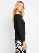Black bubble knit long-sleeve top with crinkled texture, wide neck, and subtle ruffled hem.