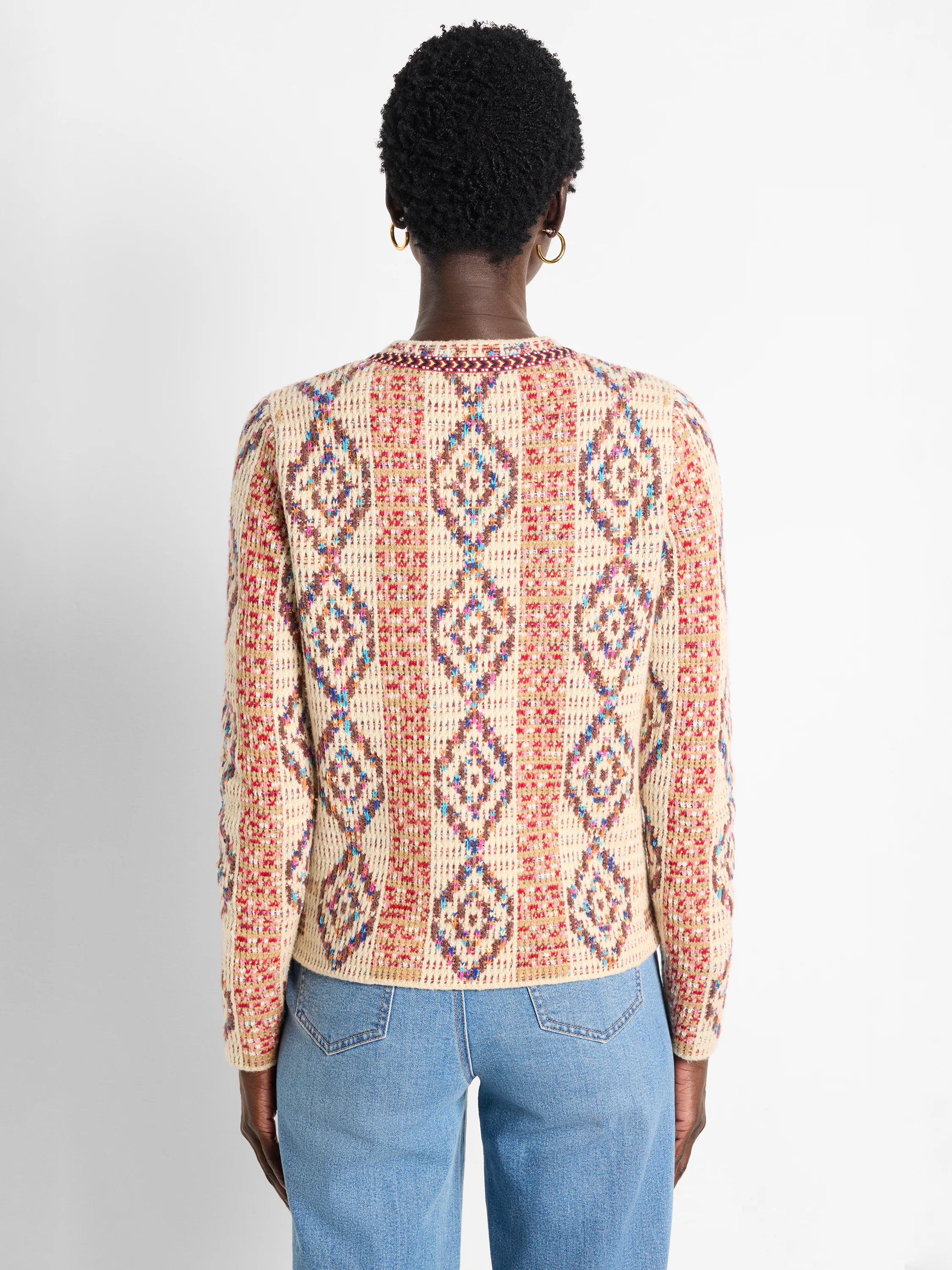 Back of a cream knit jacket with multicolored woven diamond patterns.