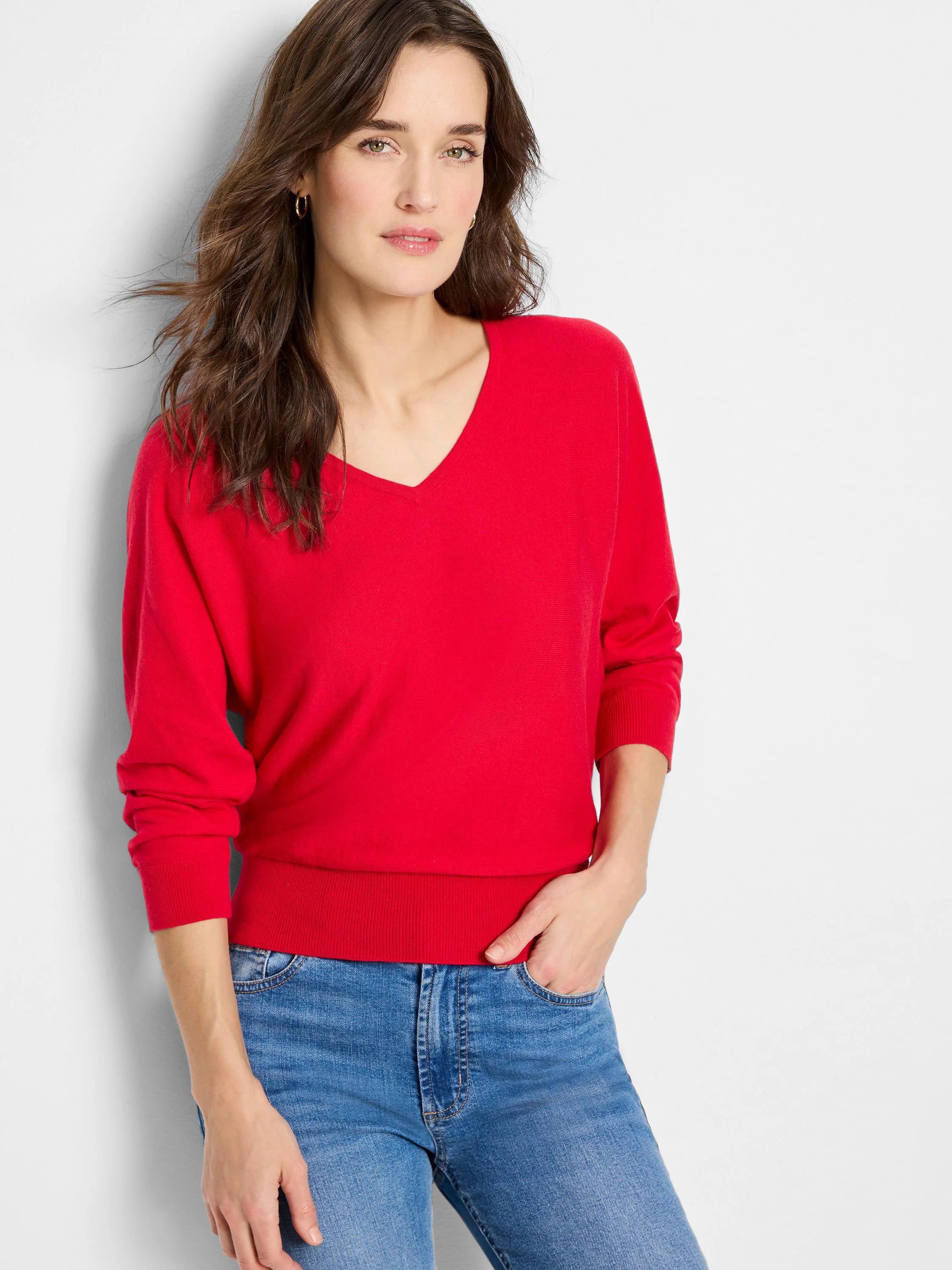 Red V-neck sweater with ribbed cuffs and hem, modeled by a woman.