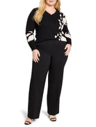 Black sweater with off-white abstract floral design on one side and a scalloped V-neck.