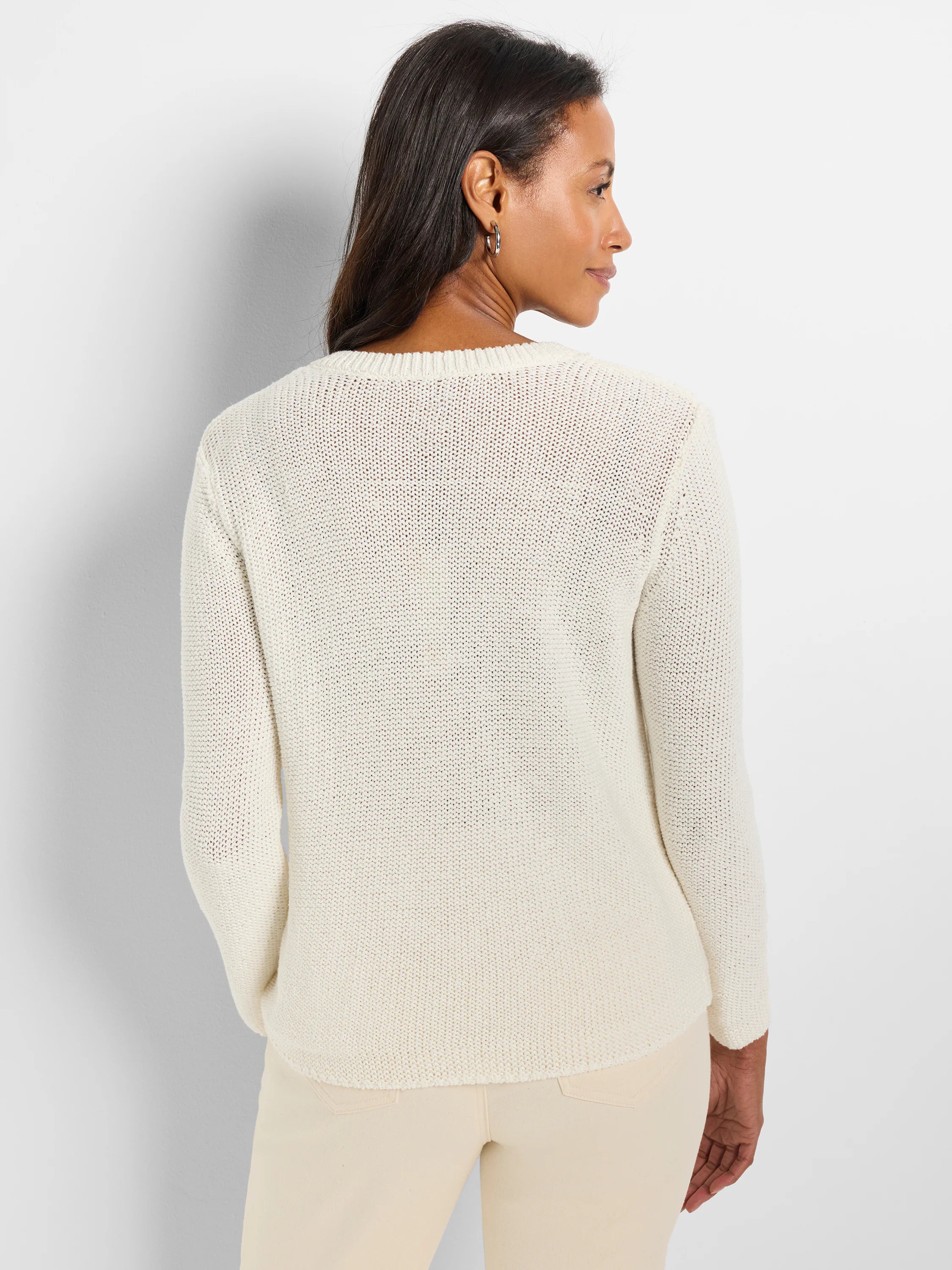 Off-white, loosely knit, long-sleeved crewneck sweater. Shown from the back.