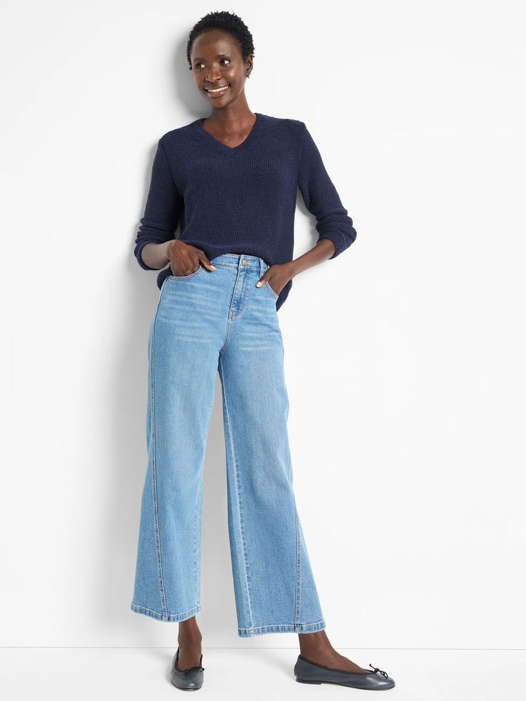 Navy blue v-neck sweater, textured knit. Model also wears light wash jeans and dark flats.