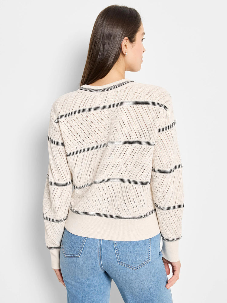 Cream-colored pointelle knit sweater with thin black and dark gray horizontal stripes. Back view.