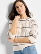 Off-white pointelle knit sweater with thin black stripes at neckline and hem; three-quarter sleeves.
