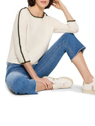 Off-white ribbed sweater with black and light green trim at neckline and sleeves.