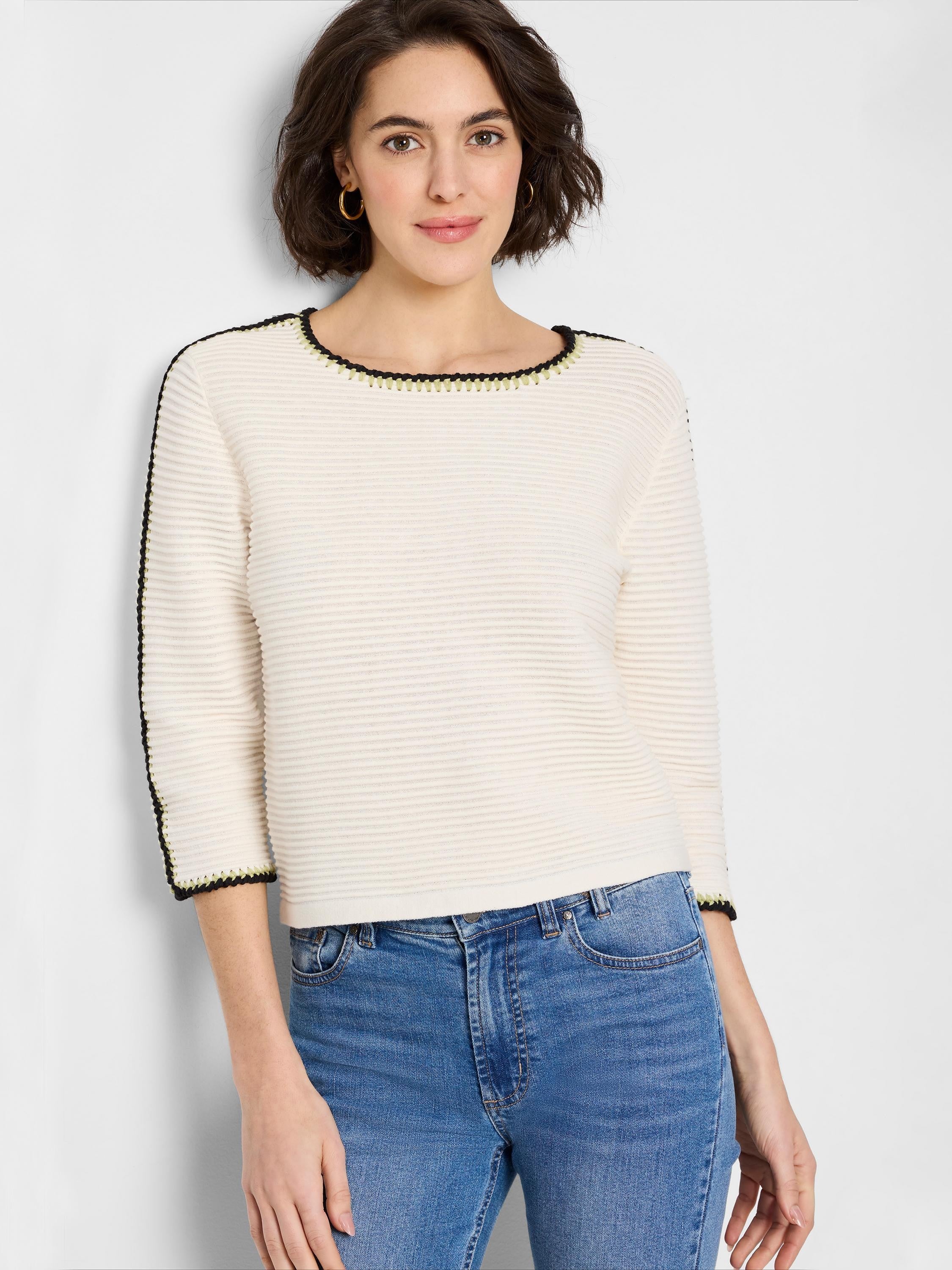 Off-white ribbed sweater with black and light-green trim at neckline and sleeves.
