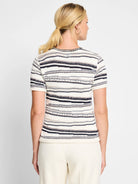 Cream-colored knit sweater tee with thin navy, brown, and cream stripes; short sleeves; crocheted neckline and hem.