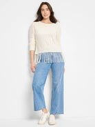 Off-white open-knit sweater with fringe bottom.  Long sleeves.
