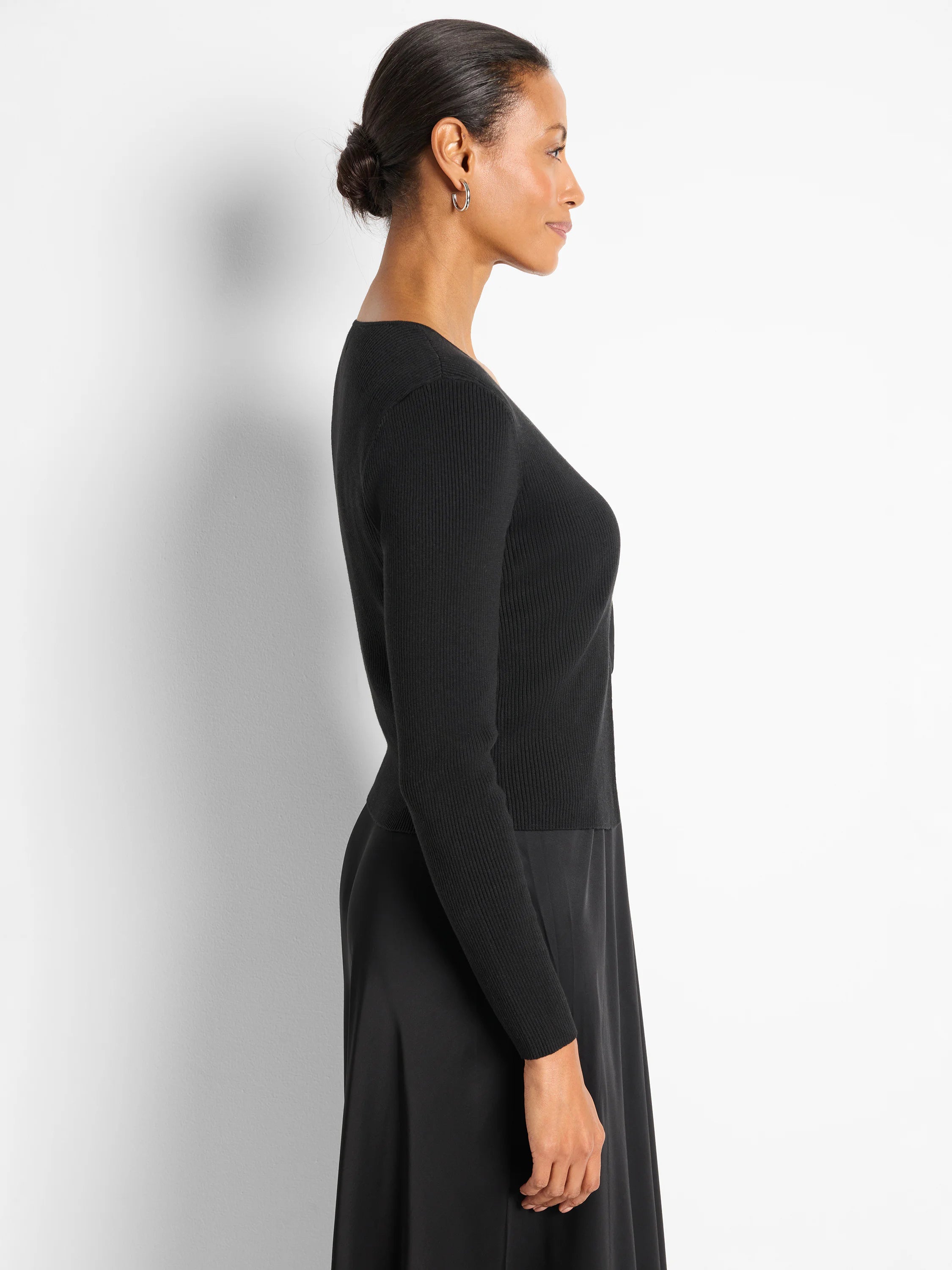 Black, ribbed, long-sleeve V-neck cardigan, shown cropped on a model in profile.