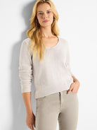 Light beige knitted V-neck sweater with a relaxed fit, featuring visible ribbed cuffs and hem. Worn by a model.