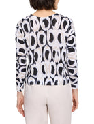 White sweater with black and beige ikat pattern. Long sleeves, crew neck.
