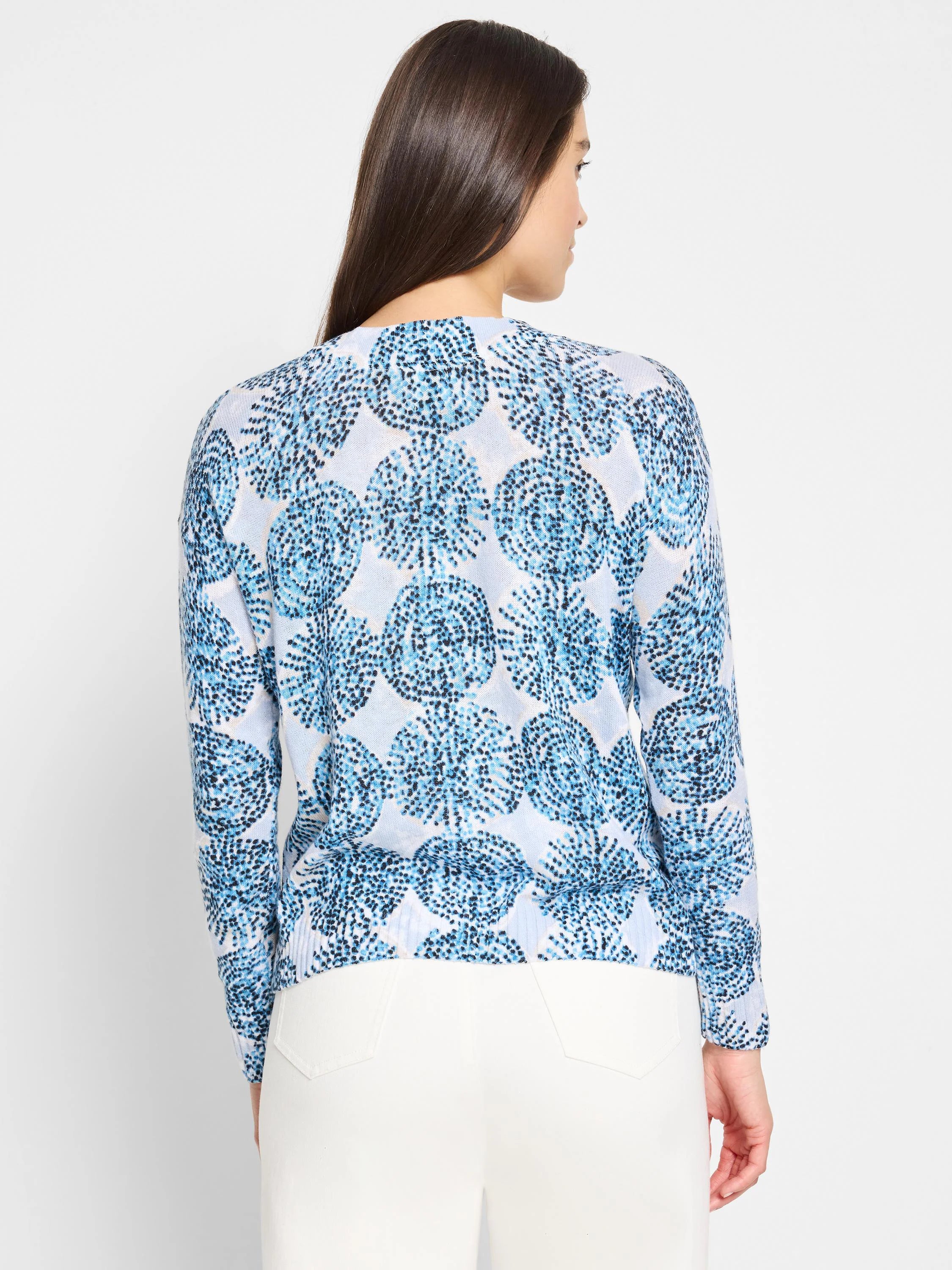 Light blue sweater with a dark blue and white patterned design of small, clustered circles. Long sleeves.