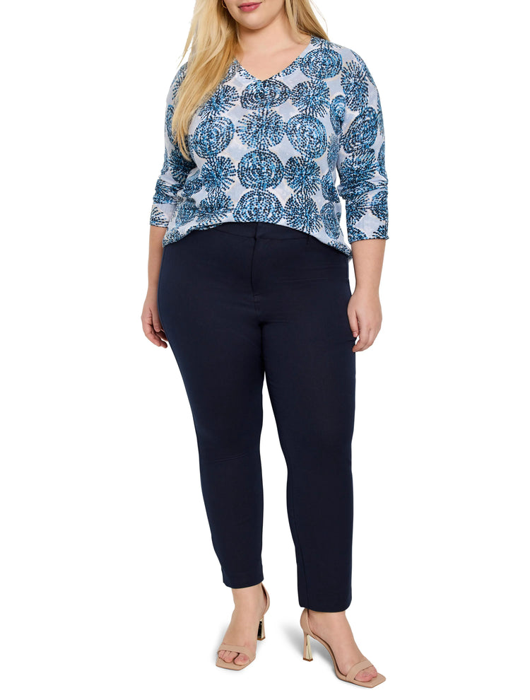 Light blue sweater with dark blue circular pattern, V-neck. Model also wears dark navy pants and light beige heels.