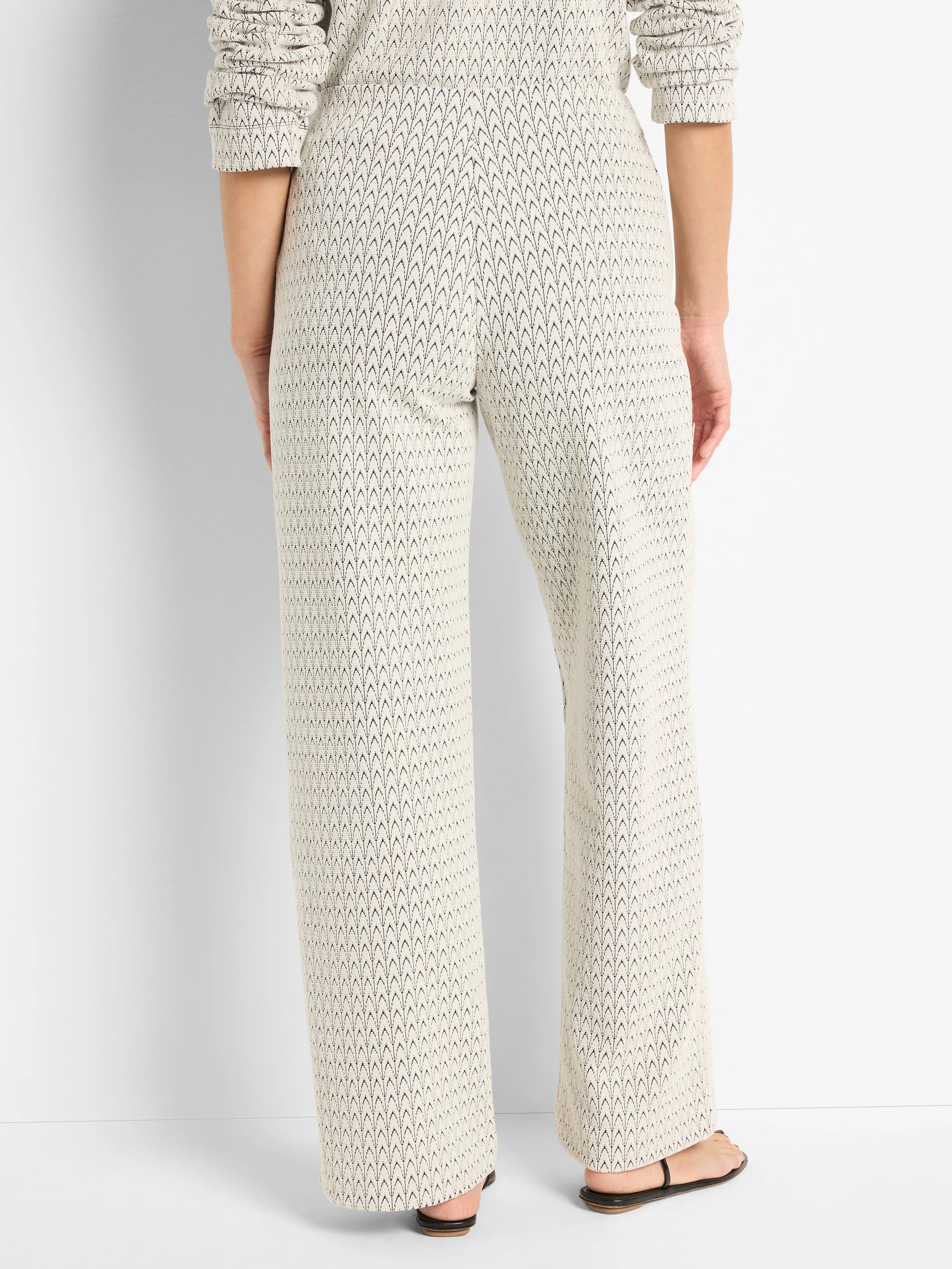 Off-white wide-leg pants with a subtle dark-grey/black repeating swirl pattern.